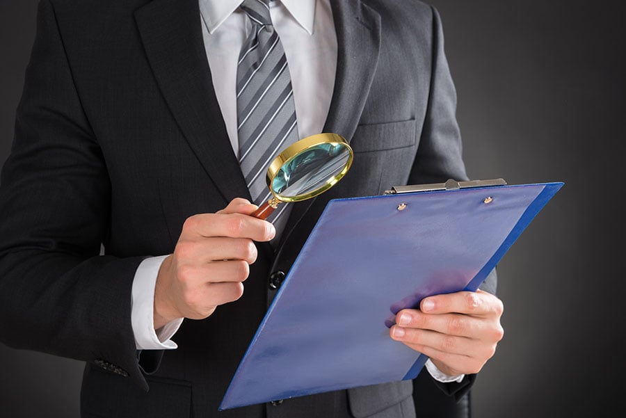 Man holding magnifying glass against document